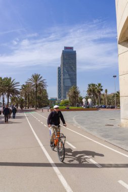 BARCELONA, İspanya - 1 Nisan 2021: Paseo de la VILLA OLIMPICA DE BARCELONA bisiklet yolunda bisiklet süren insanlar