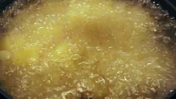 Cuchara de madera revolviendo las papas fritas en aceite en una sartén — Vídeo de stock