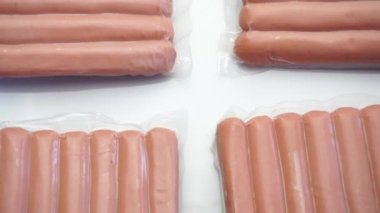 Dönen beyaz arkaplan üzerinde plastik paketlenmiş sosis paketlerinin yakın plan görüntüleri