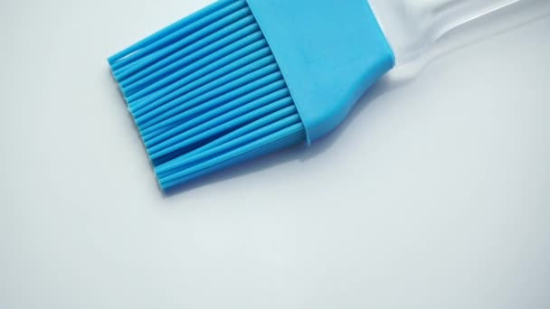 旋转的白色背景上的蓝色橡胶厨房刷子 — 图库视频影像