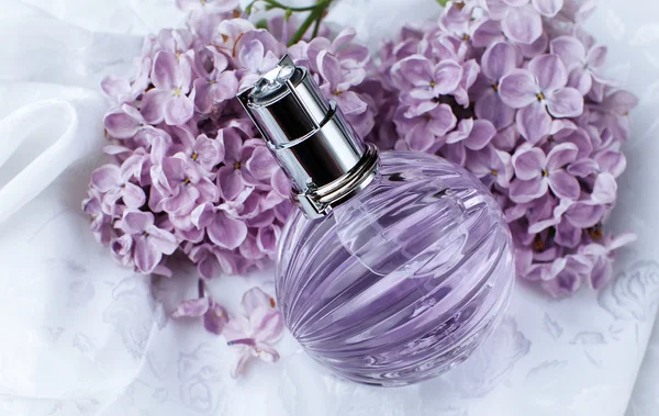 Духи и фиолетовые цветы — стоковое фото