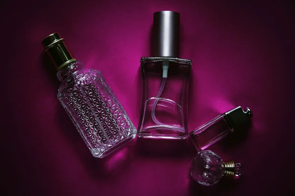Different bottles of perfume in pink background — Stock Photo, Image