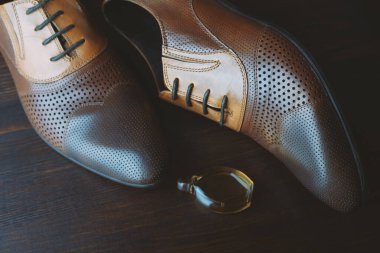 Erkek ayakkabısı ve parfümü ahşap arka planda