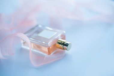 Mavi arka planda pembe kurdeleli parfüm.