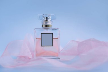 Mavi arka planda pembe kurdeleli parfüm.