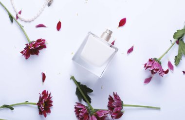 Beyaz arka planda parfüm şişesi ve çiçekler