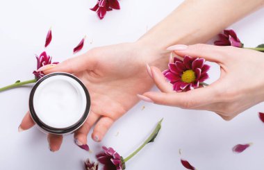 Güzel kadın elleri, krema ve çiçekler