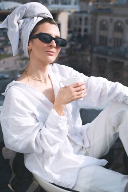 Güzel kız duştan sonra balkonda çay içiyor.