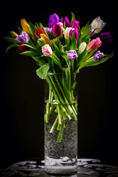 Bouquet of tulips in vase on dark — Stockfoto