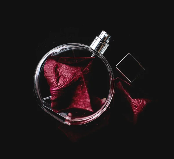 Parfum met een bloemblaadjes van roos op zwart — Stockfoto