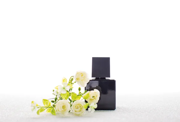Garrafa preta de perfume e uma flor — Fotografia de Stock