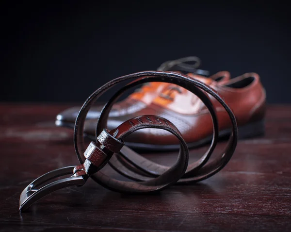 Sapatos castanhos clássicos e cinto na mesa de madeira . — Fotografia de Stock