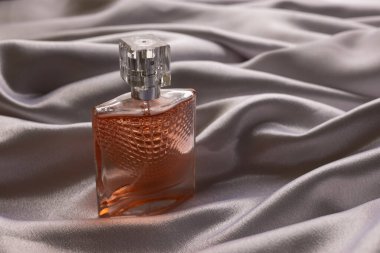 Şatafatlı parfüm şişesi ipeksi kumaş üzerinde.