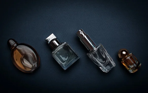 Frascos de perfume diferentes no fundo escuro — Fotografia de Stock
