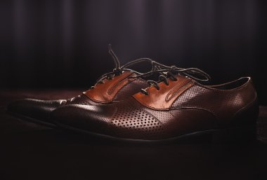 bir ahşap zemin üzerinde kahverengi deri ayakkabı