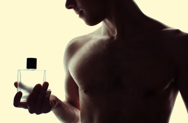 Homem bonito muscular com frasco de perfume — Fotografia de Stock