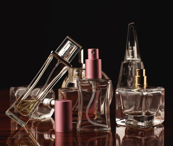 Various bottles of woman perfume on dark background. — Stock Photo, Image