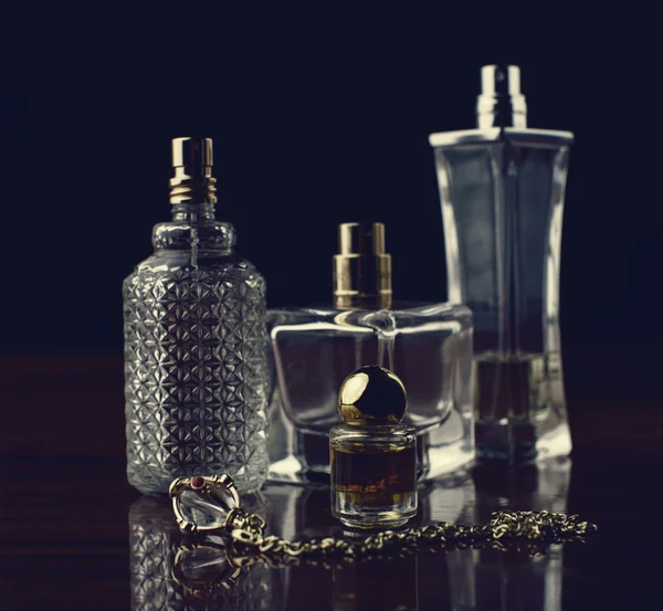 Verschiedene Flaschen Frauenparfüm auf dunklem Hintergrund. — Stockfoto