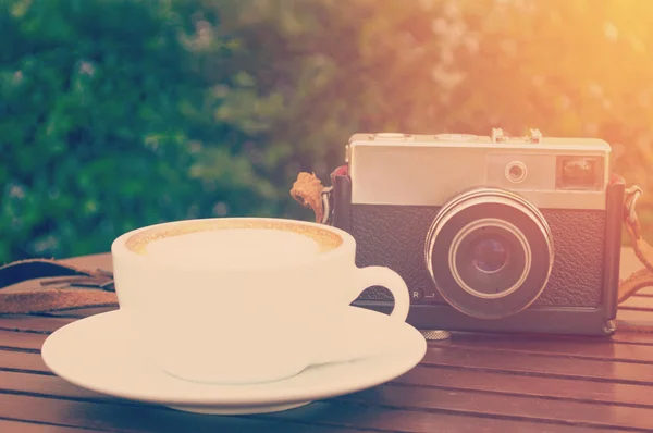 Xícara de café com câmera retro na mesa de madeira marrom — Fotografia de Stock