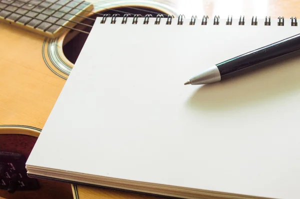 Notebook and pen on guitar — Stock Photo, Image