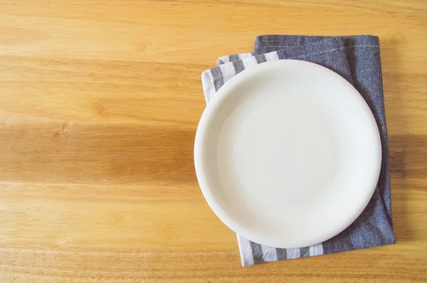 Pusty talerz i ręcznik na drewnianym tle stołu — Zdjęcie stockowe