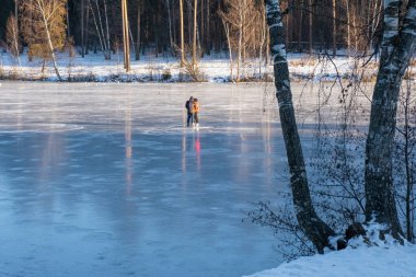 Genç çift güneşli bir günde Rusya 'da nehir buzunda paten kayıyor..