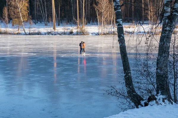 Genç çift güneşli bir günde Rusya 'da nehir buzunda paten kayıyor..