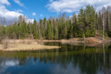 Güneşli bir bahar gününde yüksek sarp kıyıları olan küçük göl, Rusya.