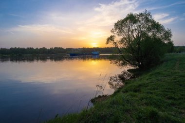 Volga Nehri üzerinde güzel turuncu-altın gün batımı ve Rusya 'nın sularındaki bulutlu gökyüzünün yansıması. 