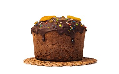 Çikolata ile dolu ve kurutulmuş meyveler, kurutulmuş kayısılar, şekerli meyveler, kirazlar, kuru üzümlerin yanı sıra fındıklar, bademler ve tohumlarla süslenmiş tatlı pasta hasır bir tezgahta duruyor. Beyaz bir arkaplanda izole edilmiş.