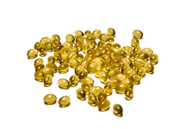 Beyaz zemin üzerine dağılmış vitaminli sarı kapsüller izole edilmiş..
