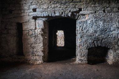 Eski kalenin bodrum tüneli. Hapishanenin taş duvarları. Birkaç oda arasında uzun bir koridor. Toprak zemin.