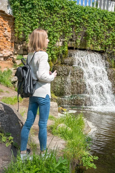 Meisje permanent in de buurt van een waterval in een park — Stockfoto