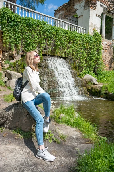 Chica sentada cerca de una cascada en un parque —  Fotos de Stock