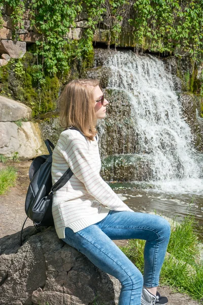 Chica sentada cerca de una cascada en un parque —  Fotos de Stock