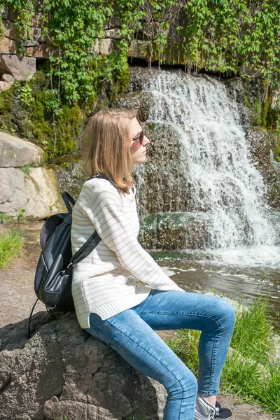 Fille assise près d'une cascade dans un parc — Photo