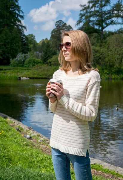 Meisje in het park met een kopje koffie — Stockfoto