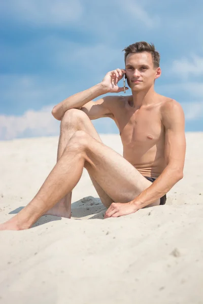 Junger, athletischer Mann mit Handy am Strand — Stockfoto