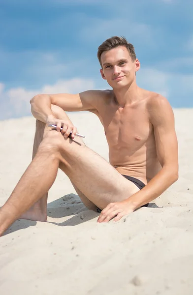 Junger, athletischer Mann mit Handy am Strand — Stockfoto