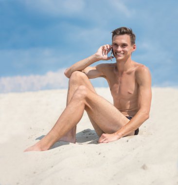 Adam sahilde cep telefonu ile genç atletik tabaklanmış.