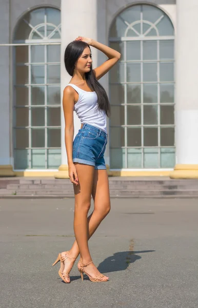 Chica en una camiseta y pantalones cortos en frente de un edificio con columnas —  Fotos de Stock