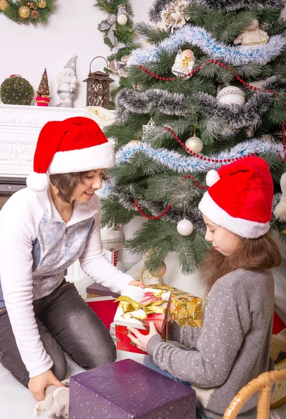 Mamá y su hija con regalos bajo el árbol de Navidad . —  Fotos de Stock