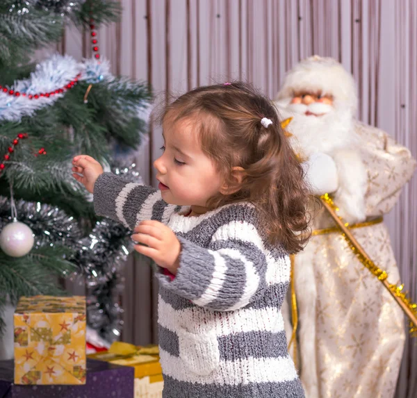 Ein Kind mit einem Geschenk den Weihnachtsbaum. — Stockfoto