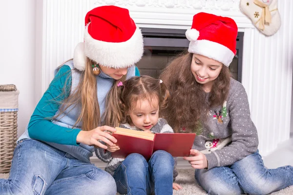 Hermanas mayores leyendo una historia de Navidad su hermana pequeña . —  Fotos de Stock