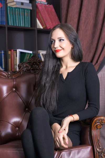 Young woman sitting in a leather chair — Stock Photo, Image