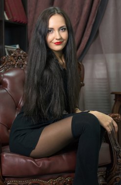 Bir deri sandalyede oturan genç kadın