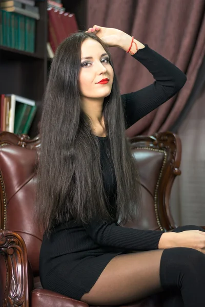 Young woman sitting in a leather chair — Stock Photo, Image