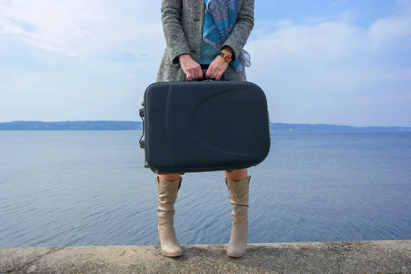 Jambes d'une femme dans une bottes et avec une valise devant le s — Photo