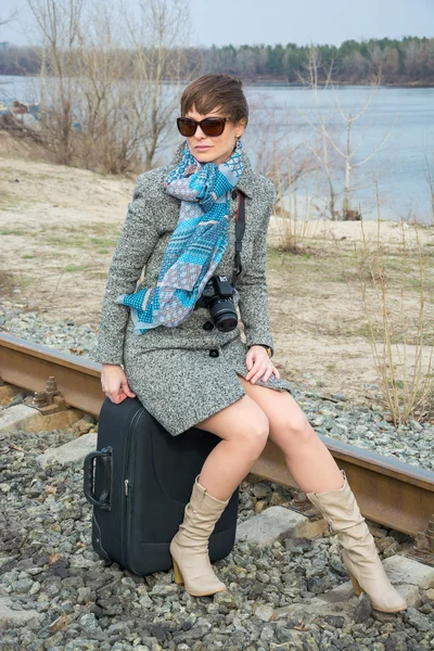 Young woman with a suitcase and a camera on the rails — Stock Photo, Image