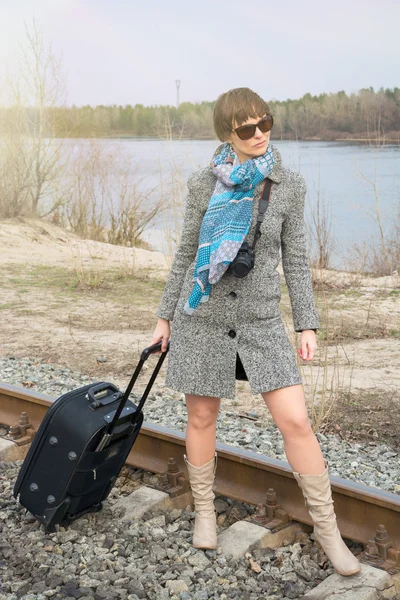 Jonge vrouw met een koffer en een camera op de rails — Stockfoto